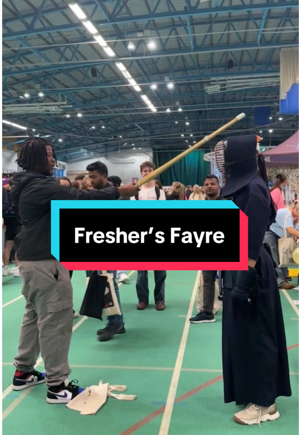 A large indoor athletics centre filled with students and young people during an events fayre, with the caption box 'Fresher's Fayre'